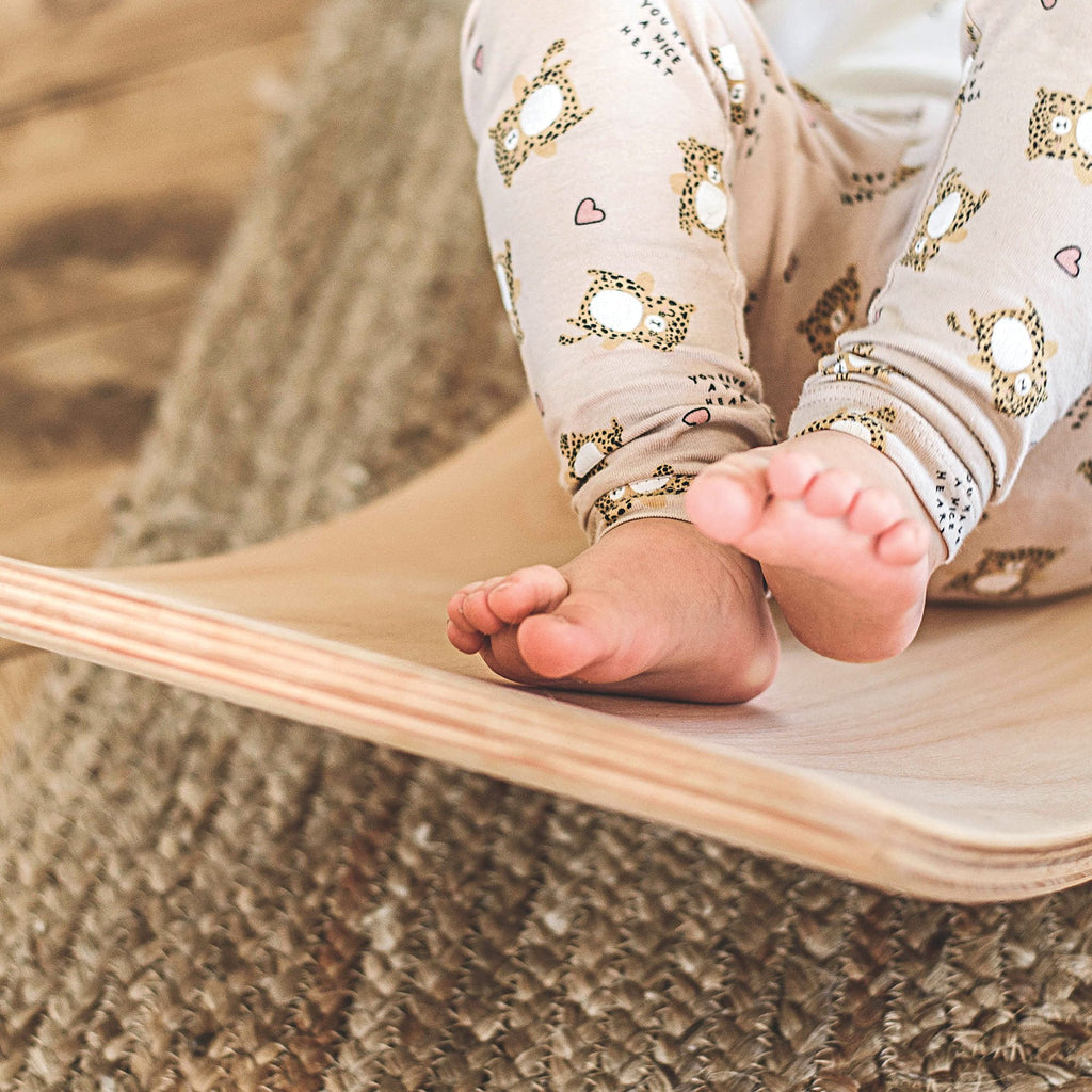 3. Close-up of child's feet on beige balance board, highlighting texture and design