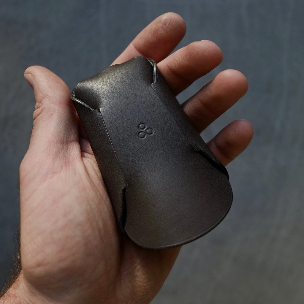 2. Back view of Mirgoods black folded keyholder in hand, highlighting unique one-piece construction