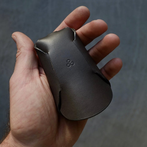 2. Back view of Mirgoods black folded keyholder in hand, highlighting unique one-piece construction