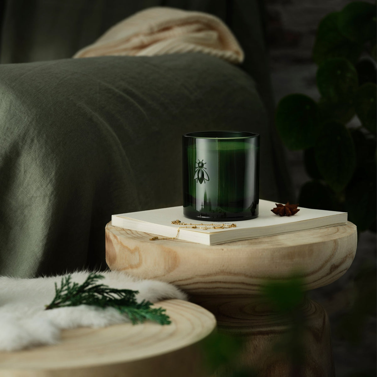 1. La Rochère Cedar Bee Candle in green glass container, styled in a cozy bedroom setting