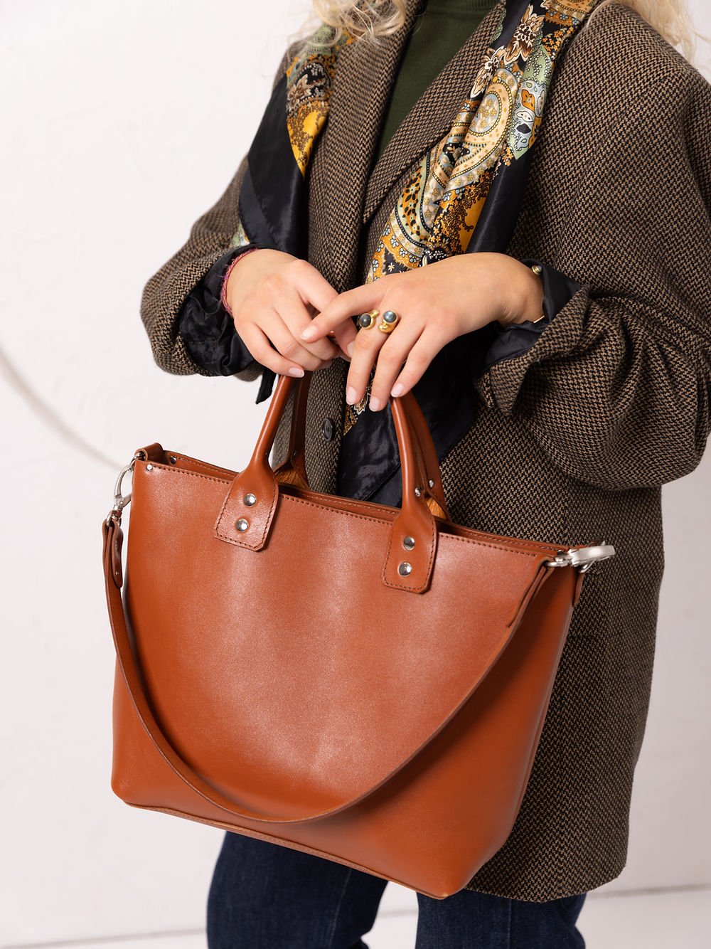 5. Close-up of woman holding TOKS VISOKS MIGLE leather handbag in ginger, showing handle details