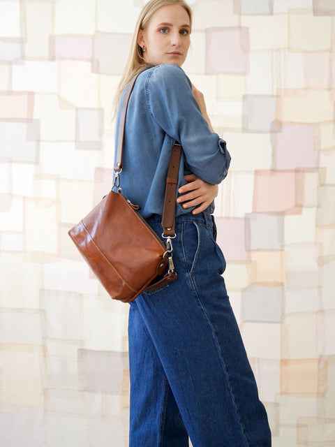 3. Woman holding TOKS VISOKS ROBIN leather handbag in ginger brown, shown from side view