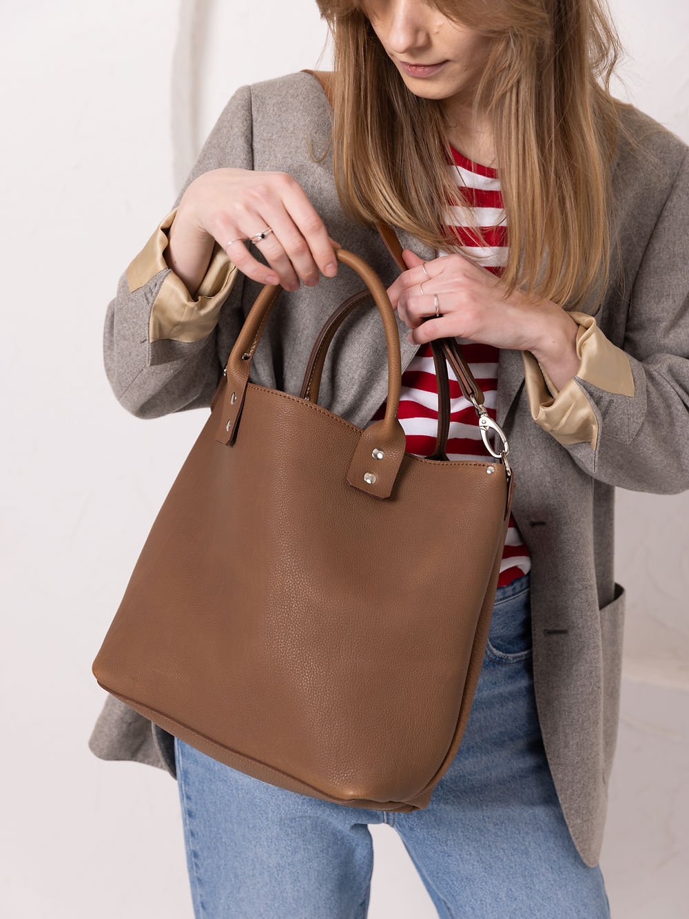 8. Woman examining MIGLE Leather Handbag in cappuccino by TOKS VISOKS, highlighting wide opening