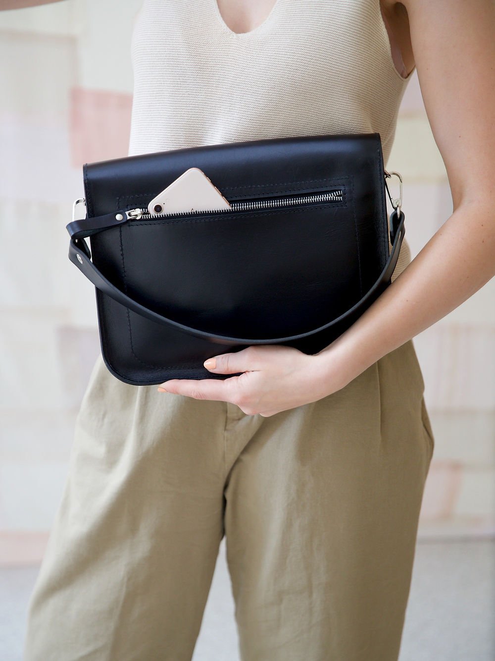 5. Close-up of TOKS VISOKS ASTORIA black handbag showing back zipped pocket with phone