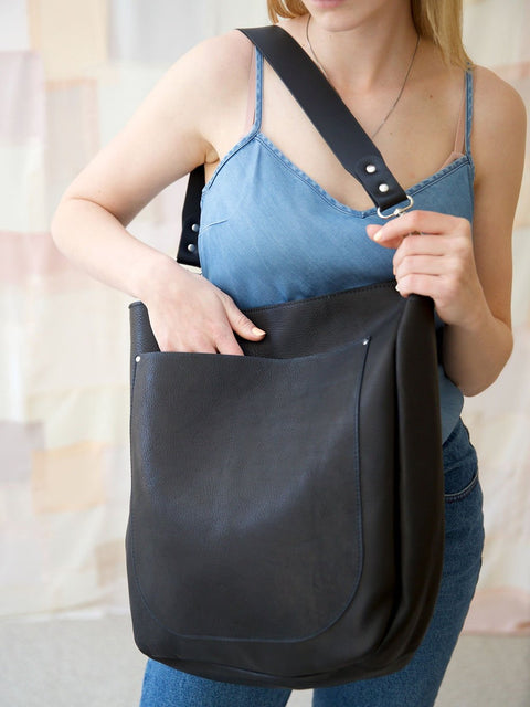 4. Woman accessing front pocket of LULU black handbag, showing functionality and style