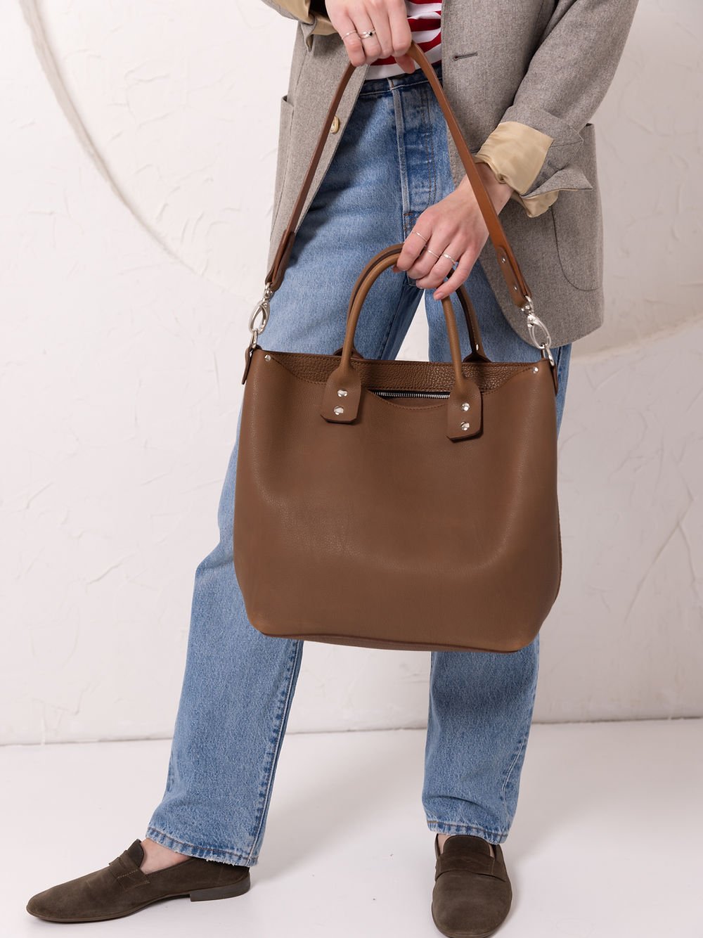 7. Close-up of woman holding MIGLE Leather Handbag in cappuccino by TOKS VISOKS, showing front view