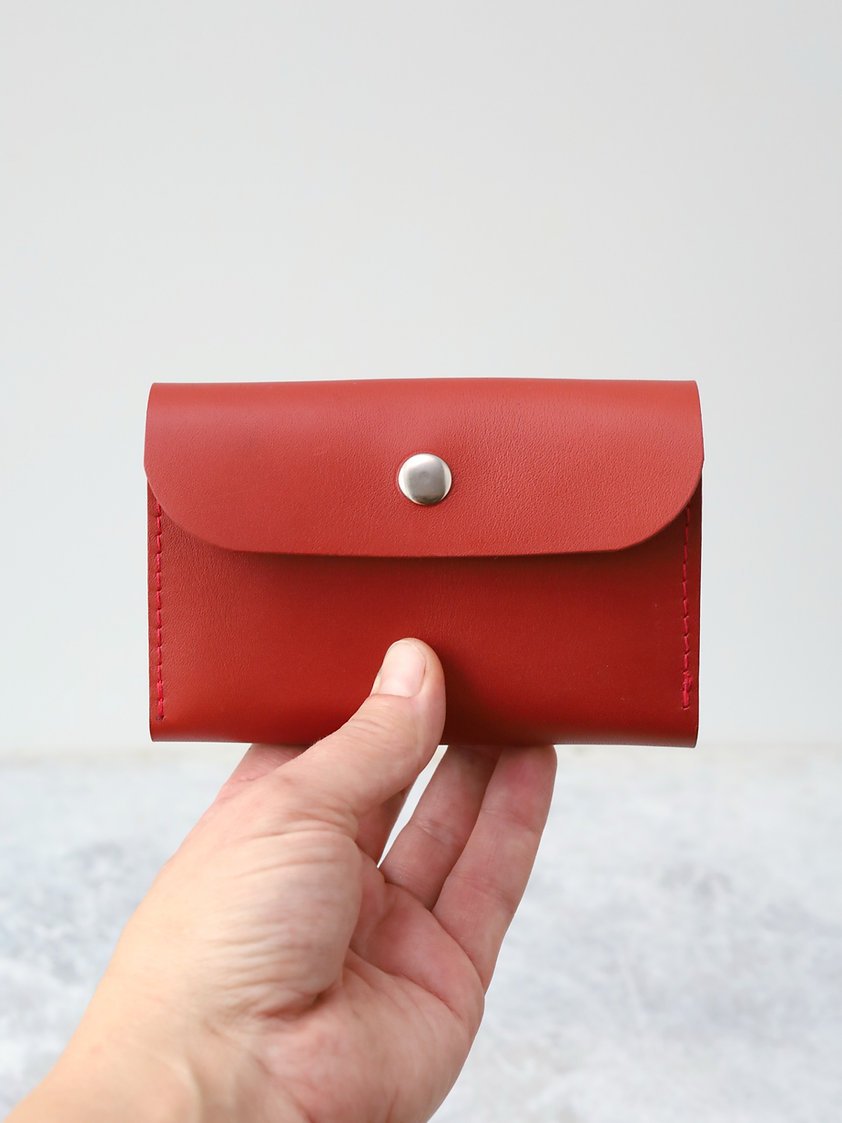 1. Hand holding TOKS VISOKS FRIDAY Wallet in faded red, showcasing compact design