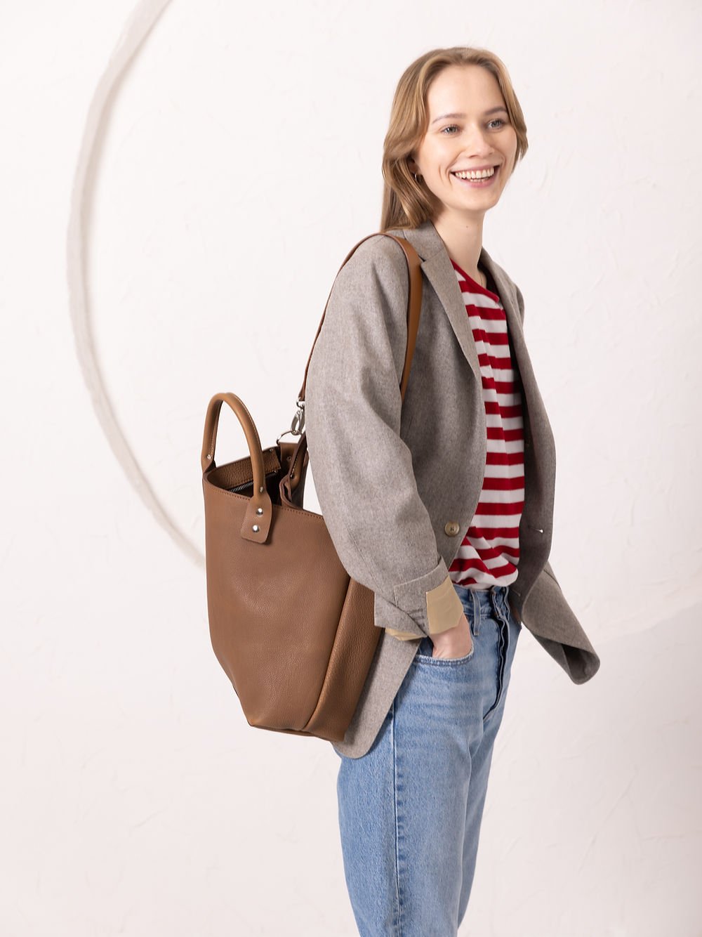 2. Woman smiling with MIGLE Leather Handbag in cappuccino by TOKS VISOKS, worn over shoulder