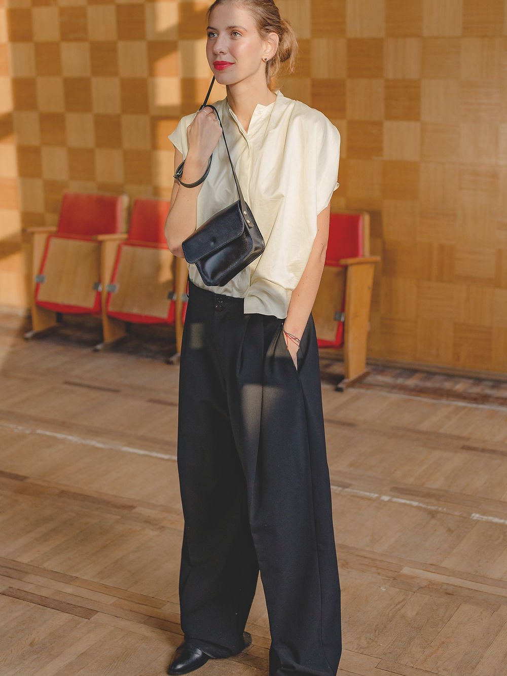 1. Women's black RUBY Purse by TOKS VISOKS worn crossbody in a stylish indoor setting