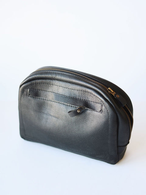 1. TOKS VISOKS black leather toiletry bag with front zipper pocket, shown in studio setting