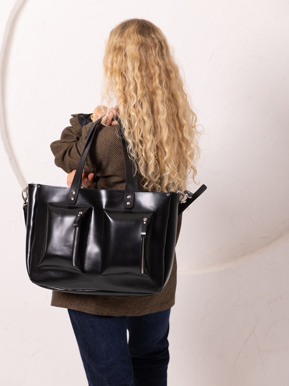 6. Women's black AMBER handbag by TOKS VISOKS, shown from the back with long handles in a studio setting