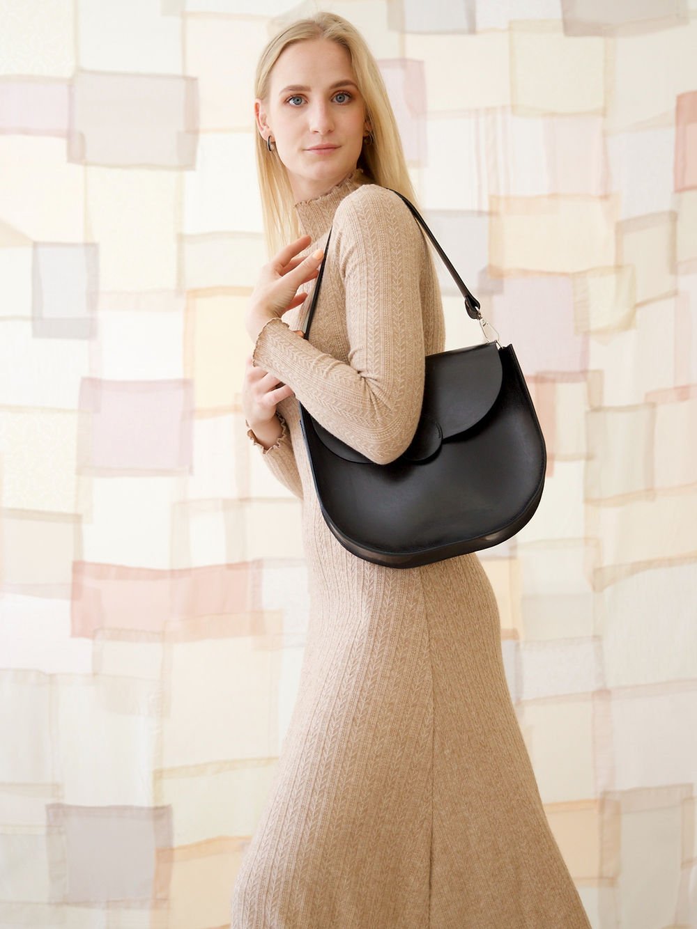 3. Woman posing with TOKS VISOKS FIONA Handbag in black, emphasizing sleek and versatile style
