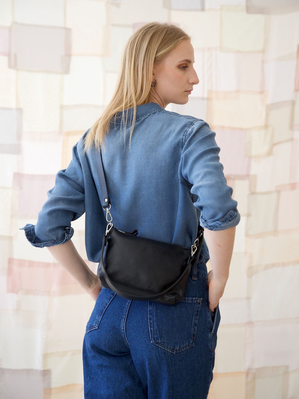 1. Women's black TOMMY leather bag by TOKS VISOKS worn crossbody, shown from the back in lifestyle setting