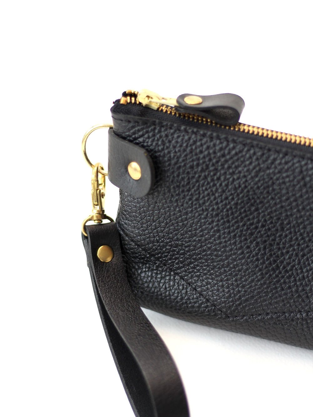 1. Close-up of TOKS VISOKS POUCH Wallet in black recycled leather with golden zipper and removable wrist strap