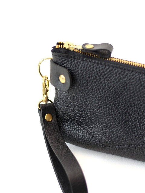 1. Close-up of TOKS VISOKS POUCH Wallet in black recycled leather with golden zipper and removable wrist strap