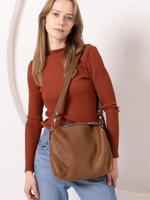 2. Close-up of woman holding TOKS VISOKS ROBIN leather handbag in camel brown, studio setting