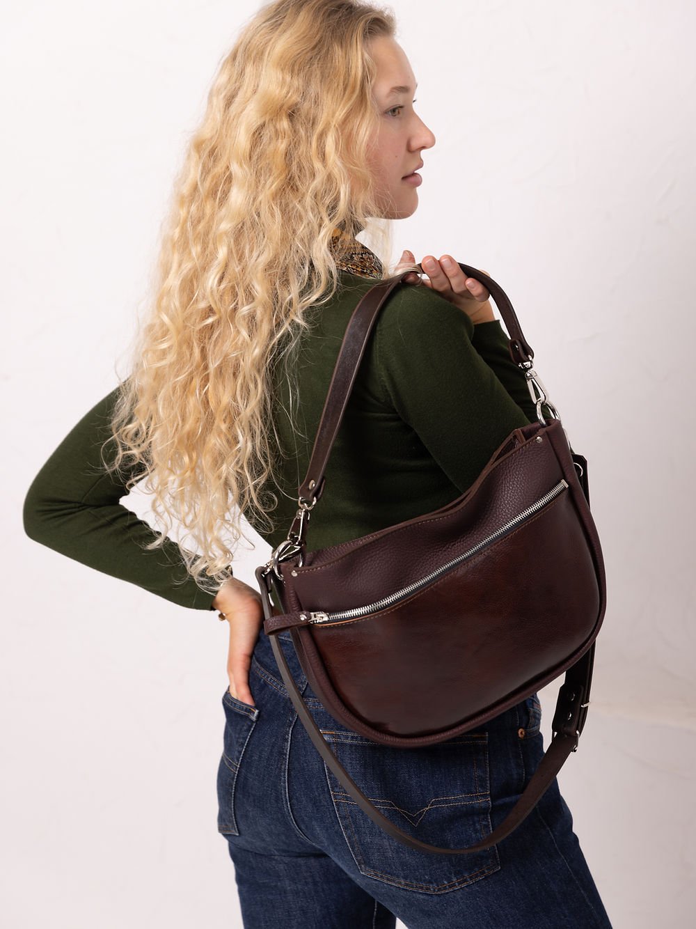 4. Woman carrying TOKS VISOKS STELLA leather handbag in brown and cognac, highlighting front pocket in studio