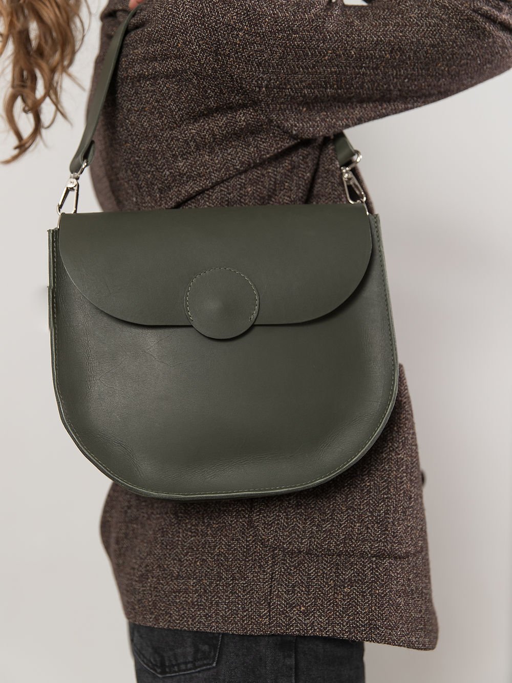 1. Woman wearing TOKS VISOKS FIONA Handbag in faded green with shoulder strap, shown in studio setting