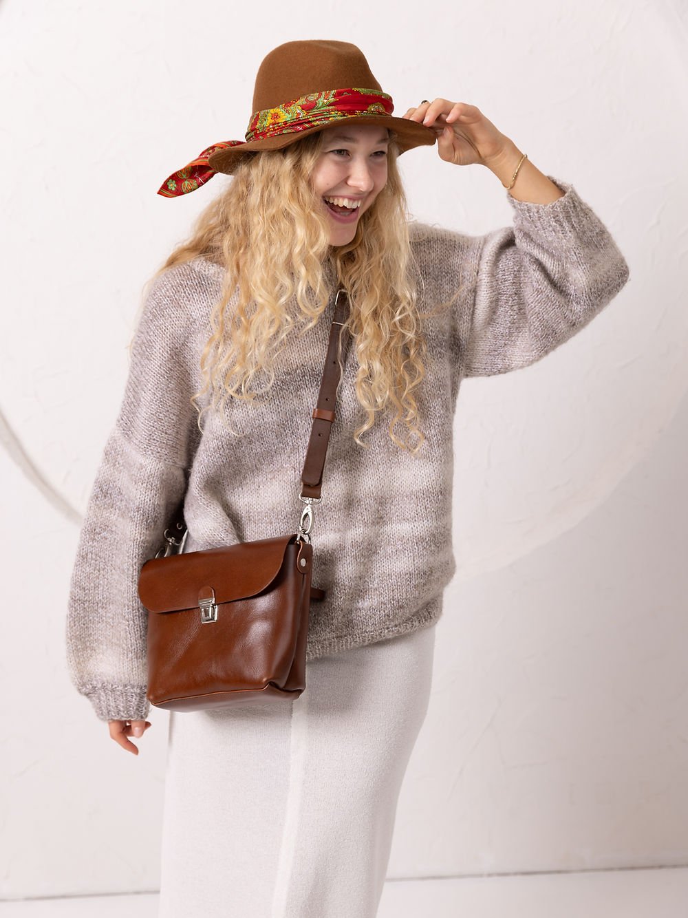 2. Woman smiling while wearing TOKS VISOKS ARLO Purse in ginger, showcasing adjustable strap and casual style