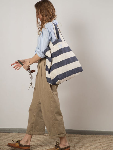 4. Woman walking with TOKS VISOKS striped canvas beach bag, lifestyle setting