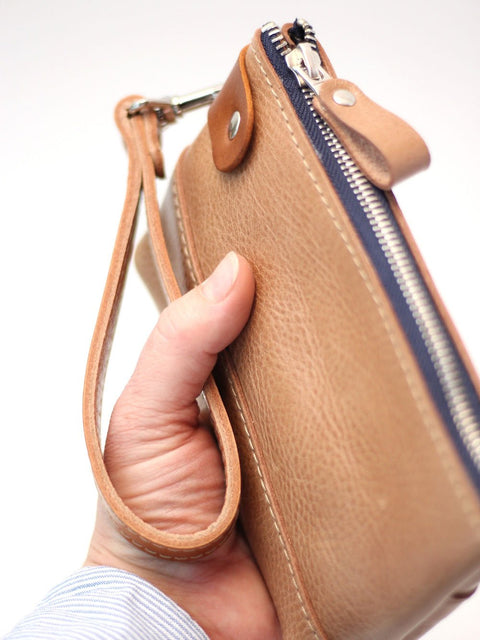4. Close-up of brown leather POUCH Wallet by TOKS VISOKS held in hand, highlighting texture and zipper