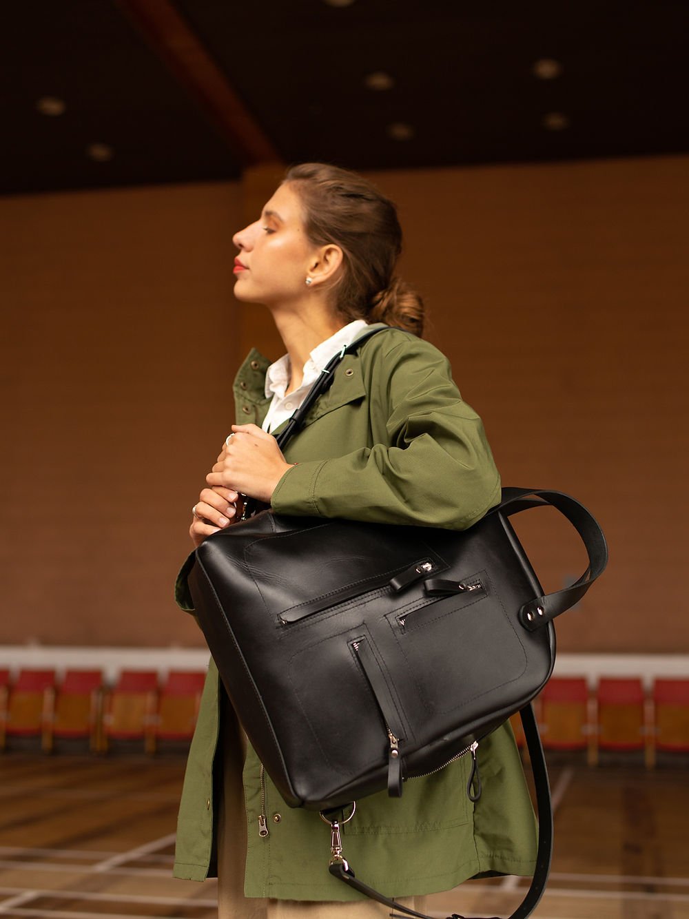 2. Woman carrying TOKS VISOKS GORDON black leather backpack on shoulder, highlighting sleek design in lifestyle setting