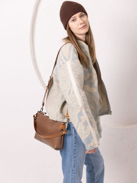 2. Woman carrying TOKS VISOKS TOMMY leather bag in cappuccino, showing side view with removable strap