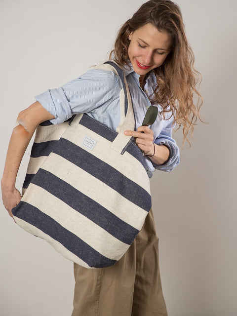 3. Woman smiling with TOKS VISOKS oversized beach bag in reclaimed stripe canvas, lifestyle image