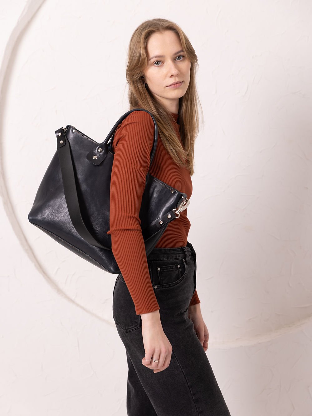 3. Women's MIGLE Leather Handbag in Dark Denim by TOKS VISOKS, shown from side in lifestyle setting