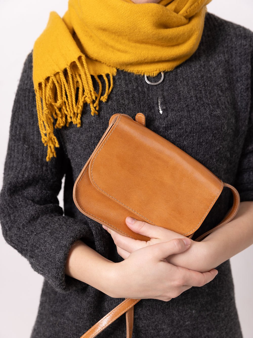 2. Close-up of TOKS VISOKS RUBY Purse in caramel leather, held by woman with yellow scarf