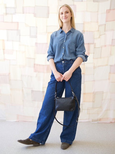 3. Women's black TOMMY leather bag by TOKS VISOKS held by model in lifestyle setting