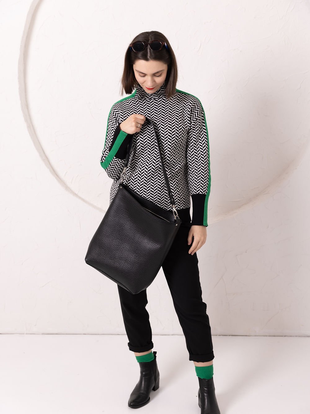 4. Woman looking down at ADDISON Leather Tote in black, emphasizing wide opening and easy access