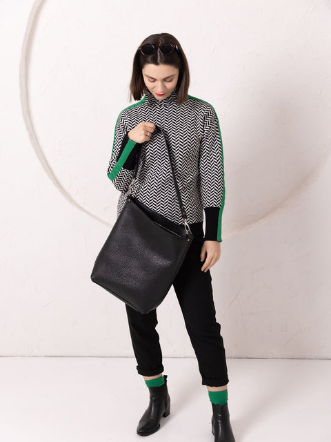 4. Woman looking down at ADDISON Leather Tote in black, emphasizing wide opening and easy access