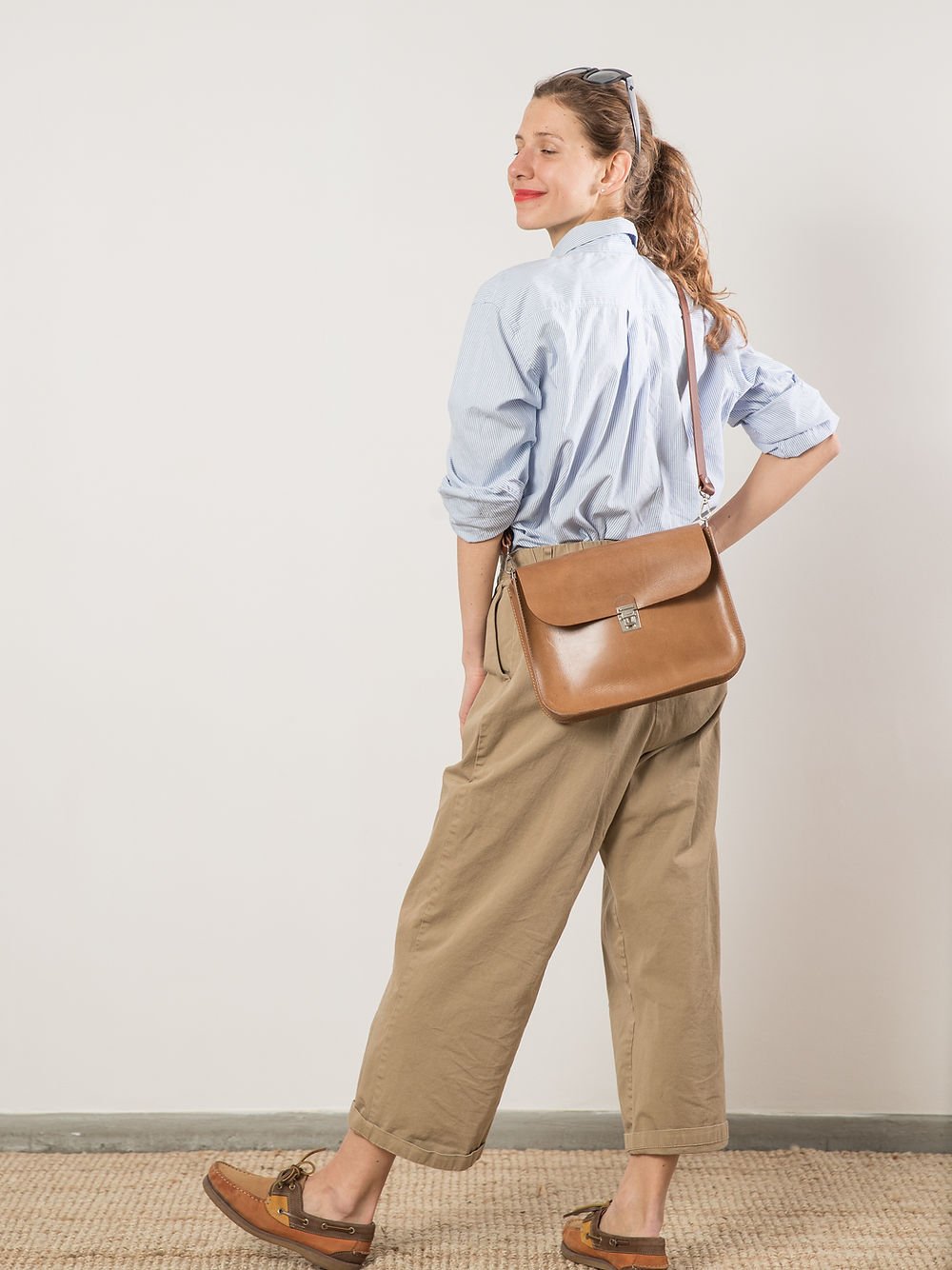 2. Woman showcasing TOKS VISOKS ASTORIA handbag in camel brown, perfect for evening outings