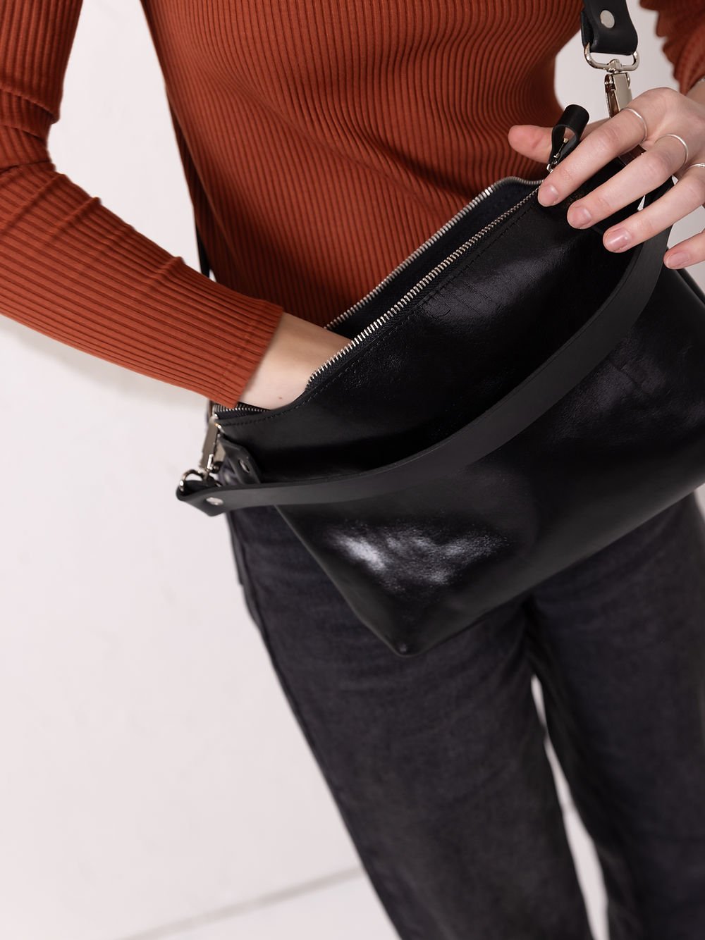 10. Close-up of black TOMMY leather bag by TOKS VISOKS showing hand accessing interior