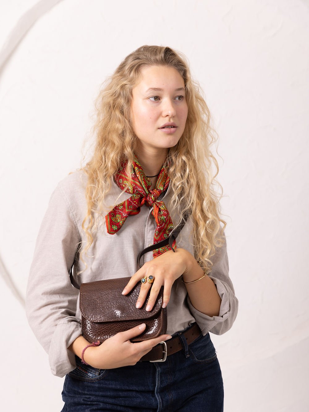 2. Woman holding brown marble RUBY Purse by TOKS VISOKS, styled with a red scarf in a studio