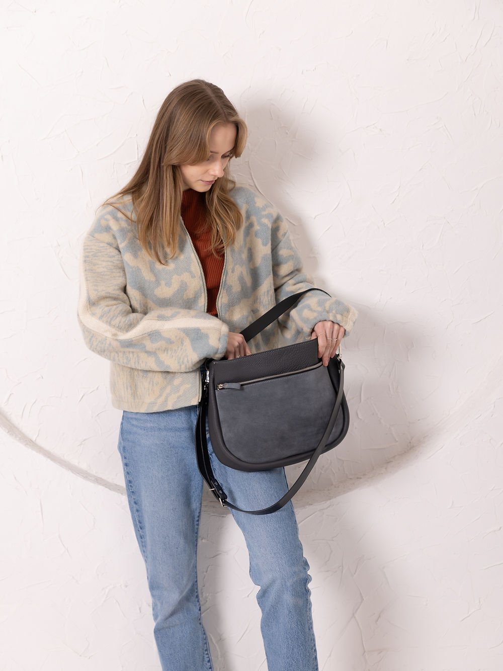 5. Woman adjusting TOKS VISOKS STELLA grey leather handbag with suede front pocket, shown in studio