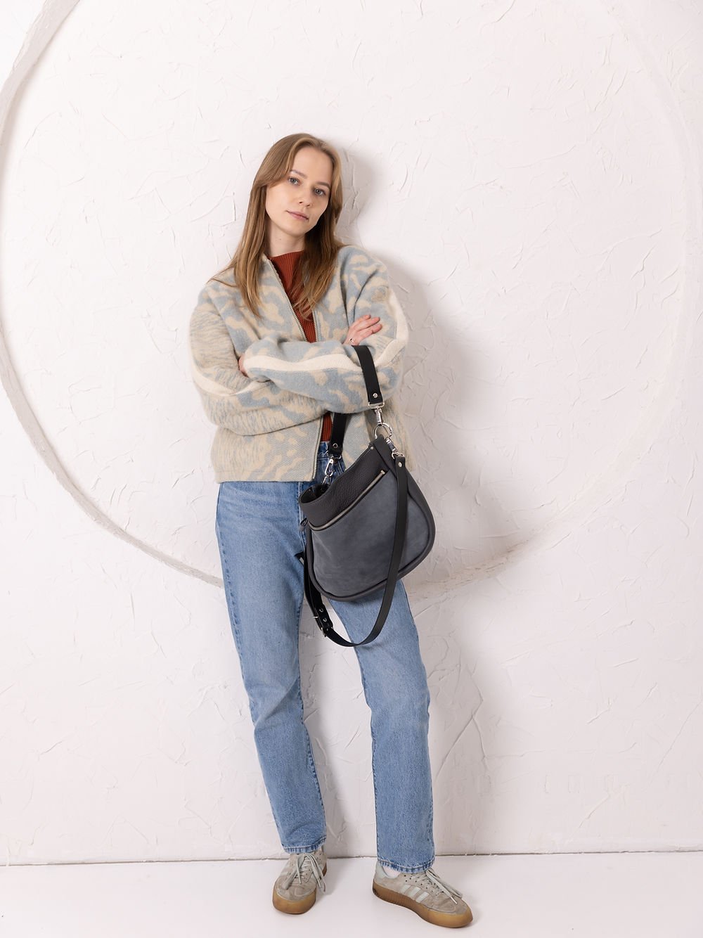 4. Woman holding TOKS VISOKS STELLA grey leather handbag with suede detail, styled casually in studio