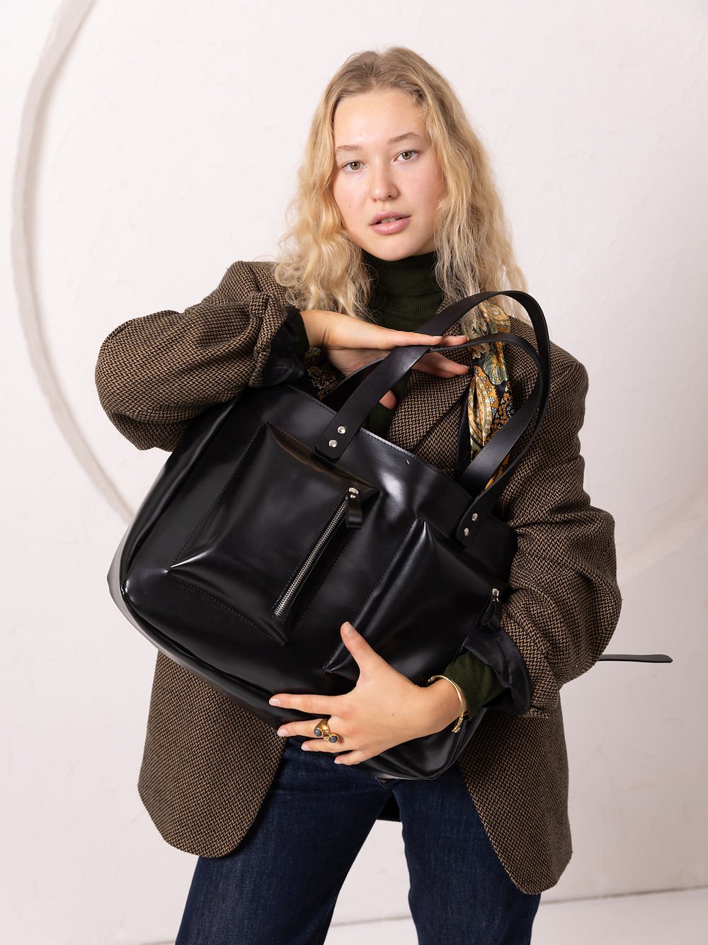 2. Women's black AMBER handbag by TOKS VISOKS, held by a model in a studio setting