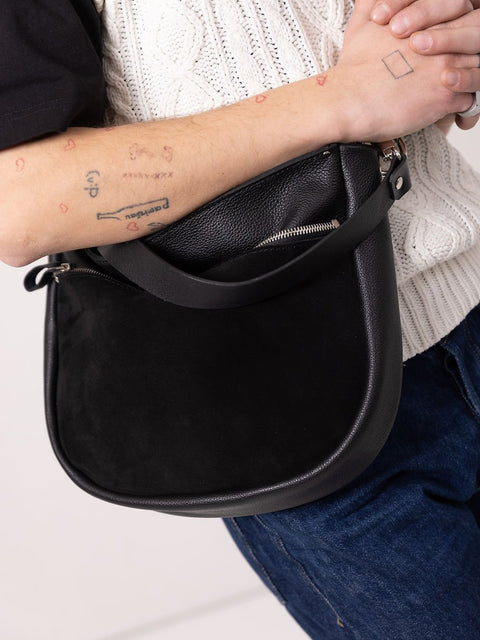 4. Close-up of TOKS VISOKS STELLA black leather handbag with suede front pocket, held by model in studio