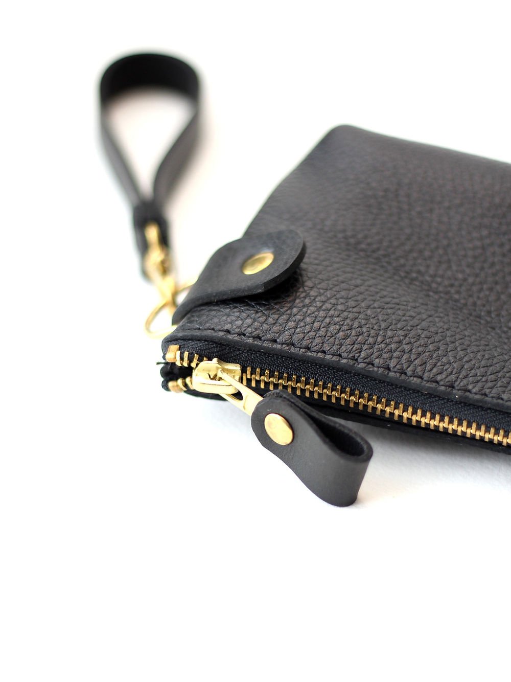 4. Detailed view of TOKS VISOKS POUCH Wallet's zipper and wrist strap in black leather with golden accents
