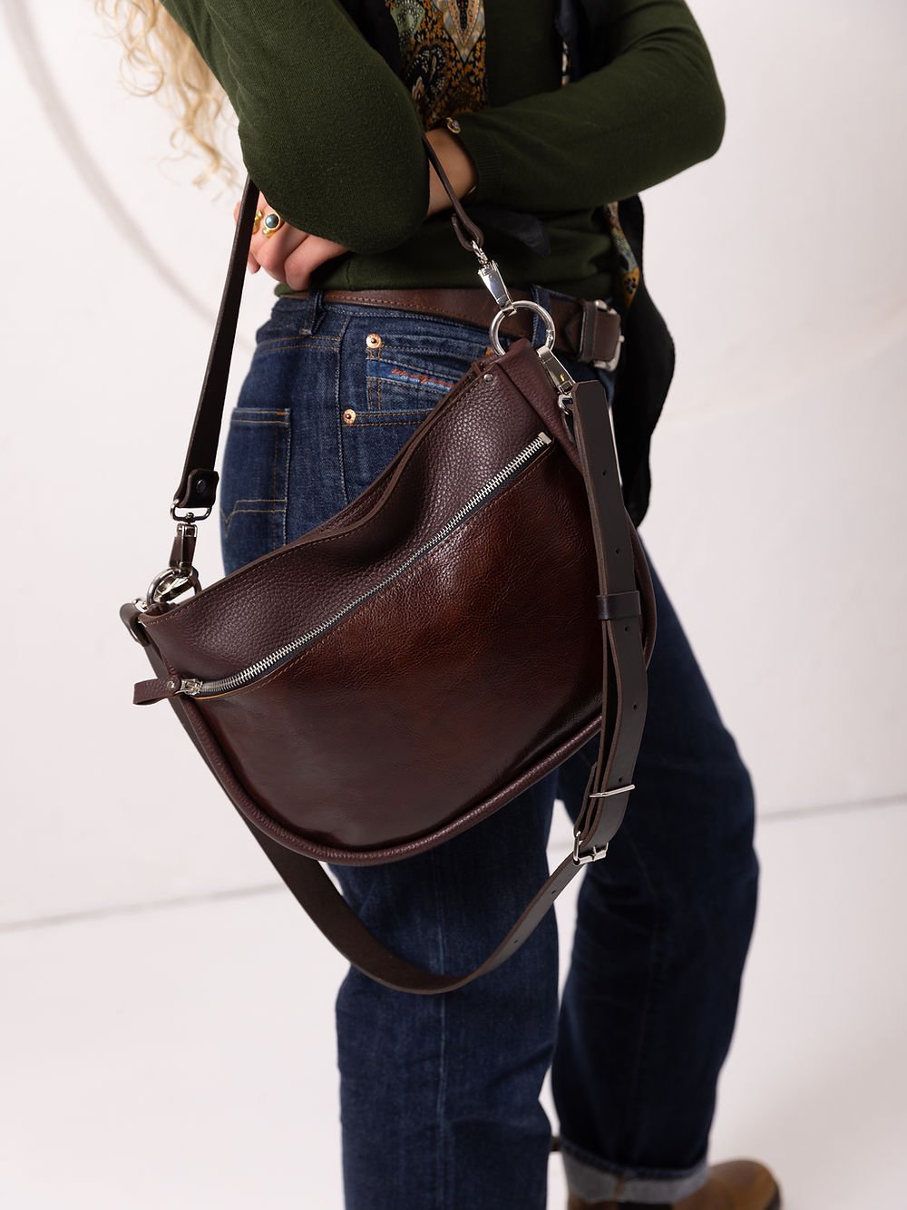 3. Woman holding TOKS VISOKS STELLA leather handbag in brown and cognac, showing adjustable strap in studio