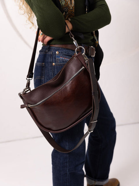 3. Woman holding TOKS VISOKS STELLA leather handbag in brown and cognac, showing adjustable strap in studio