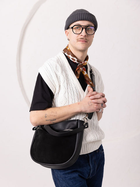 5. Unisex model holding TOKS VISOKS STELLA black leather handbag, styled with casual outfit in studio