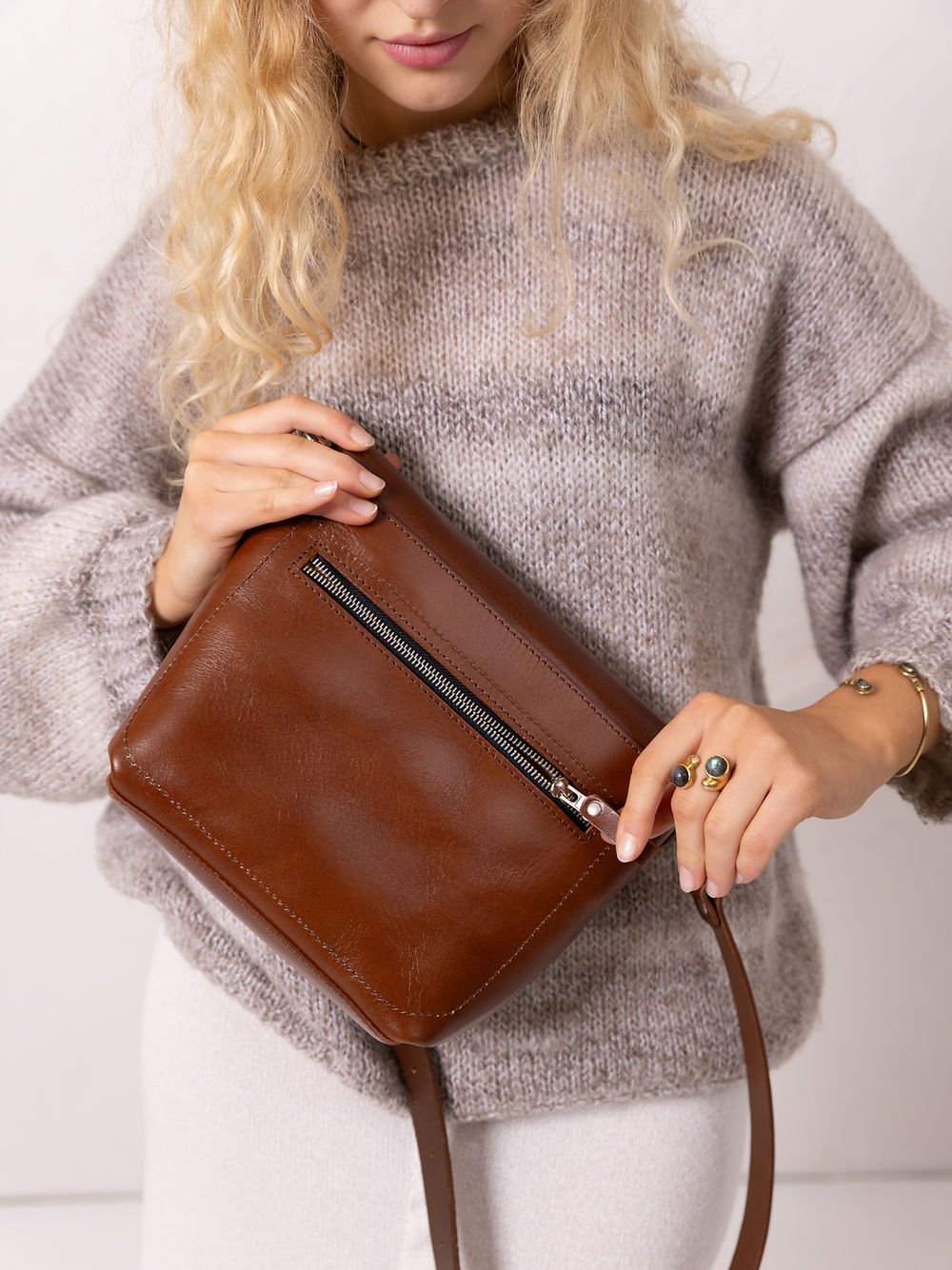 3. Close-up of woman holding TOKS VISOKS ARLO Purse in ginger, highlighting zipped back pocket and leather texture