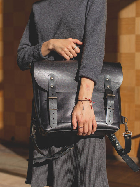 4. Close-up of woman holding black leather BENJAMIN Backpack by TOKS VISOKS, highlighting front design