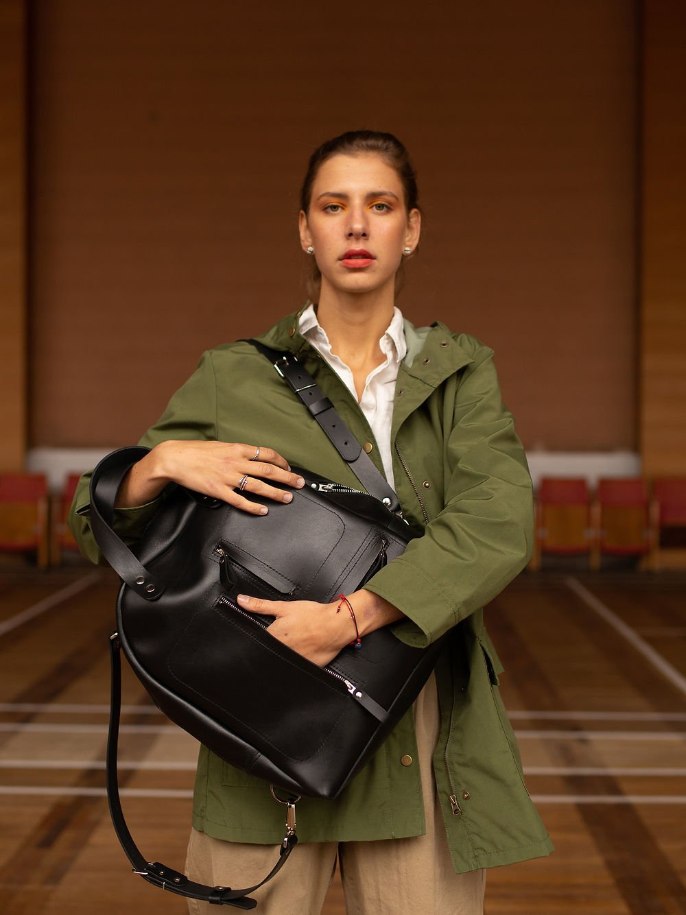 4. Woman holding TOKS VISOKS GORDON black leather backpack, emphasizing versatile carrying options in lifestyle setting