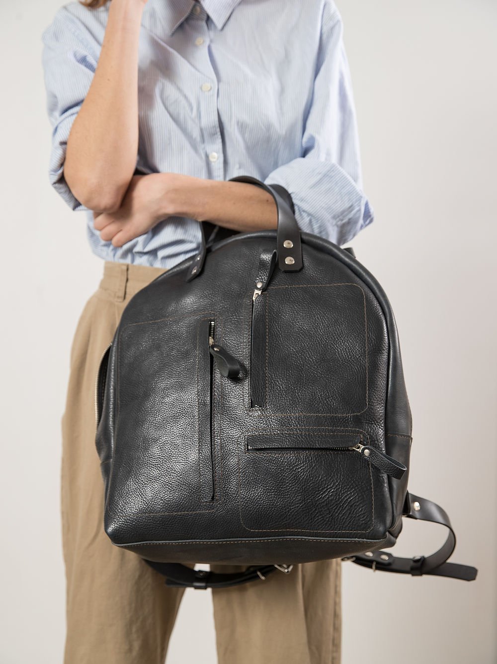 9. Close-up of TOKS VISOKS GORDON Backpack in dark denim, focusing on front pocket details and leather finish