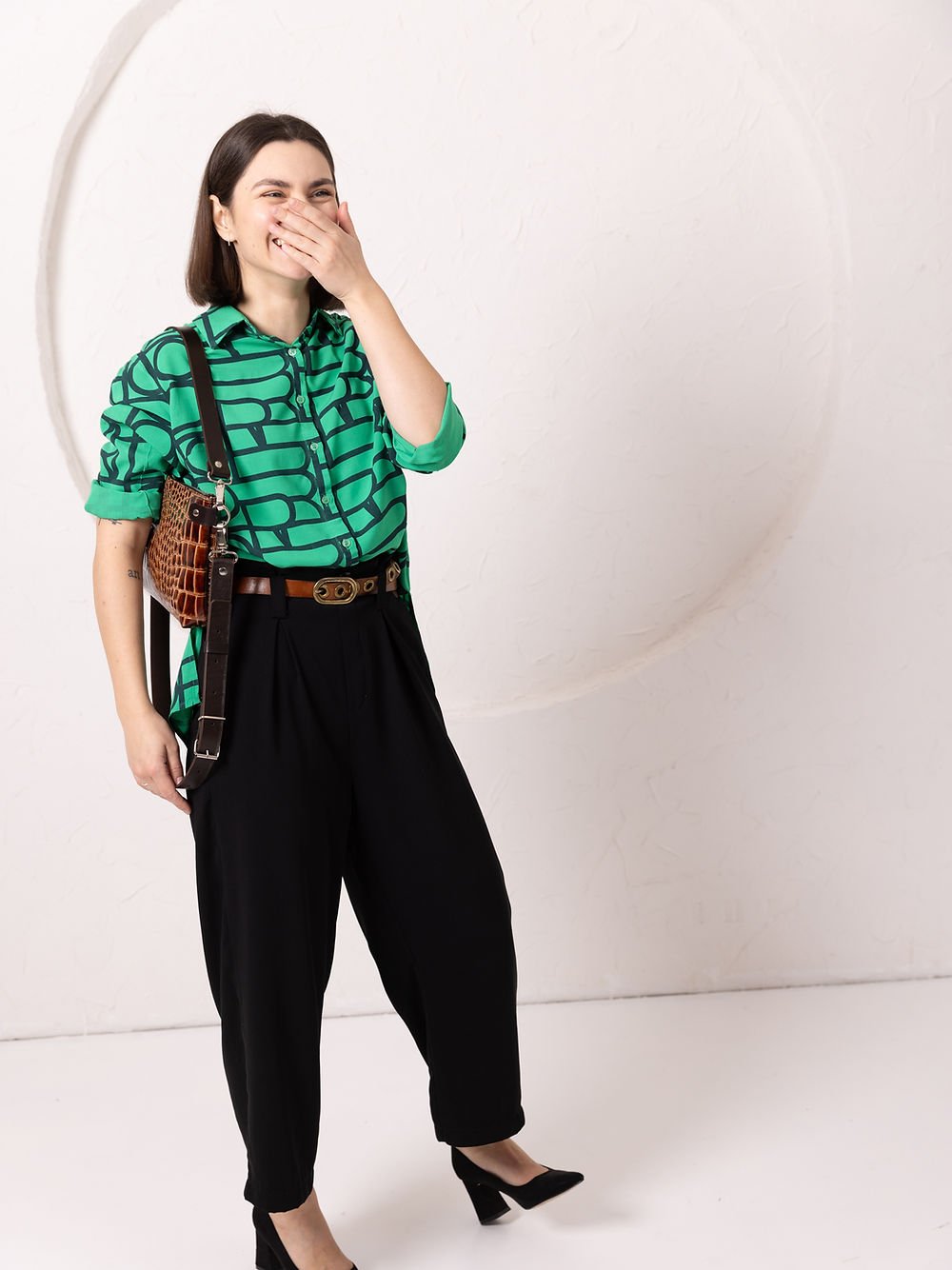 4. Woman laughing while wearing TOKS VISOKS TOMMY leather bag with alligator pattern, styled with green shirt