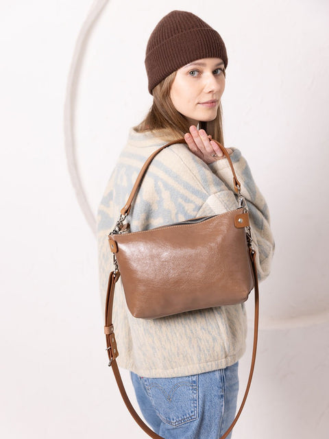 1. Woman wearing TOKS VISOKS TOMMY leather bag in cappuccino with adjustable strap, styled casually